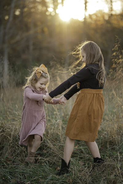 Two sisters spin around together in the sunset at Prospect Farms