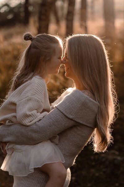 Close-up van moeder en dochter die samen neuzen tijdens een gezinsshoot.