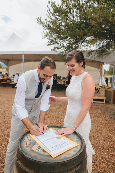 A bride and groom signing their wedding license after during their mountain reception