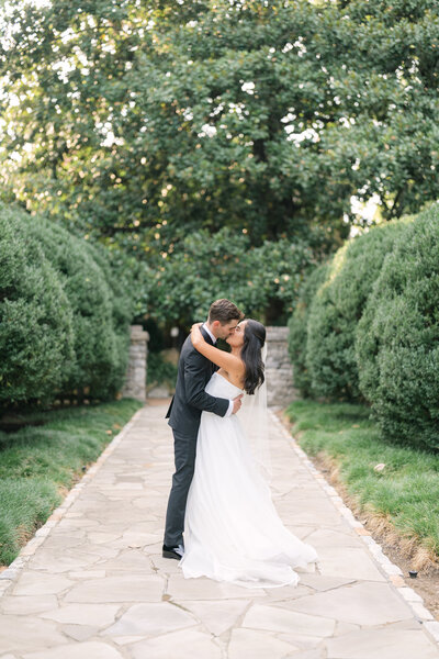 Bride and groom share a romantic kiss surrounded by lush greenery during their Nashville garden wedding, captured by Diana Marie Photography.
