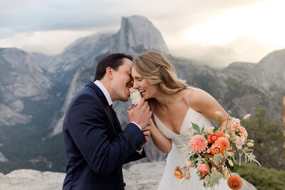 A bride and groom laugh together in front of a beautiful mountain view on their mammoth lakes wedding day. 