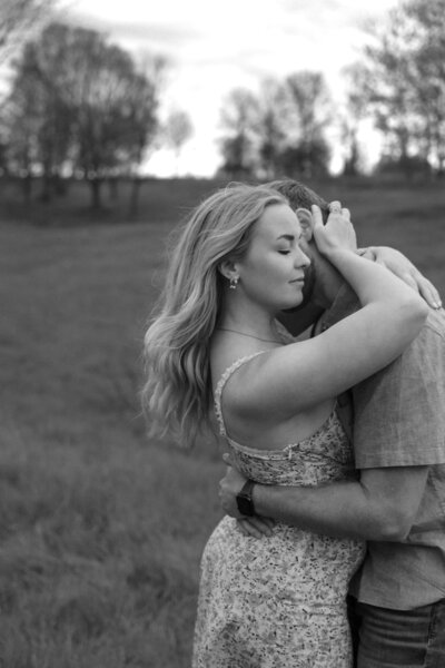 Engaged couple holding eachother during their outdoor engagement session at a scenic Kentucky park, captured by Abby Dutra Photography.