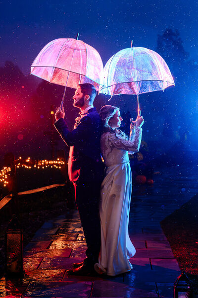 wedding couple with umbrellas in the rain with blue and red colors