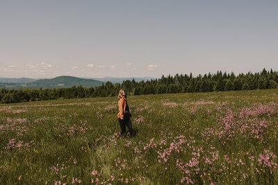 A person walking through a tall field of grass and flowers 