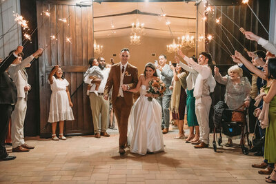 Couple exits their reception at Cypress Creek Farmhouse outdoor wedding venue in Orlando.