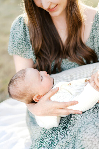 mom cradles baby in outdoor newborn photo session by portland family photographer samantha shannon