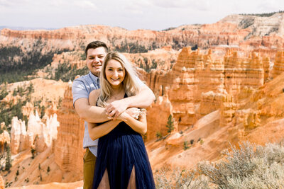 bride and groom sitting on rocks with Lake superior in the background and tall, green, pine trees