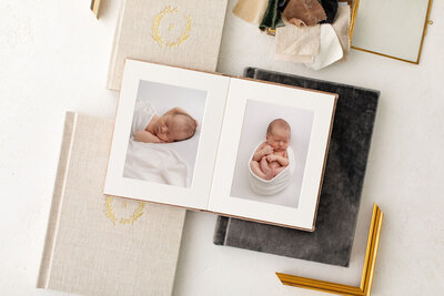 Two matted album pages of a sleeping baby wrapped in white swaddle . Sample albums from Portland newborn photographer.