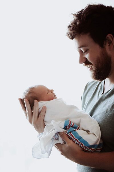 A proud new father holds his newborn baby close in a heartfelt fresh 48 hospital photo.