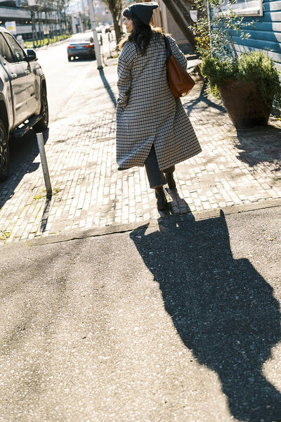 Eugene web designer Carrie walking on a sidewalk and looks over her shoulder. 