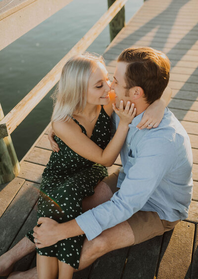 Couple sitting on the dock leaning in for a kiss