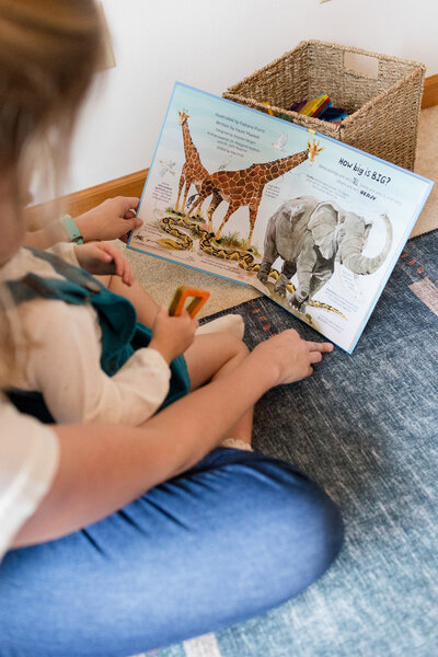 Mother reading a book about animals to their small child