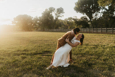 Two brides in a field during sunset, one dips the other while dancing