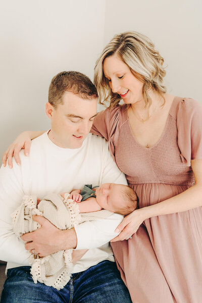 mom and dad snuggle together while dad holds baby boy for newborn photos