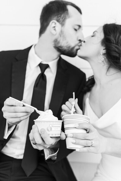 bride and groom kissing while holding ice cream