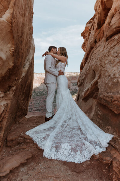 couple embracing and kissing between two big rocks in the desert