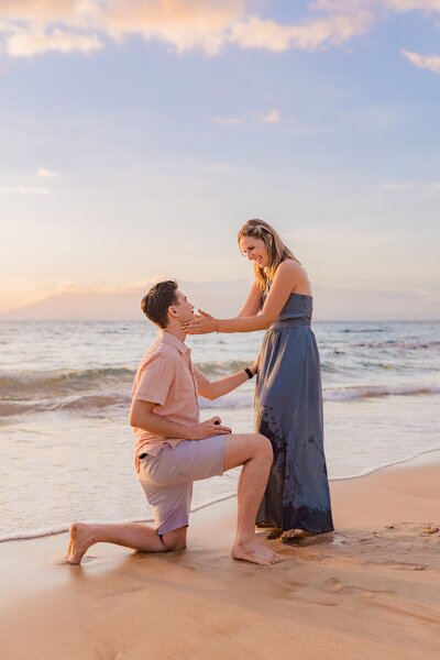 Man gets down on one knee during a surprise proposal photoshoot on the beach