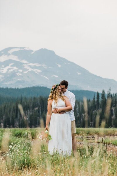 A couple kisses under a clear umbrella at the base of a waterfall in Oregon.