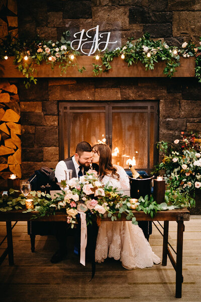 Sweetheart table in front of the fireplace at Tetherow Resort with flowers on mantle and table
