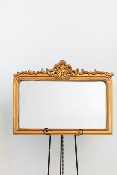 Gold rectangular mirror with ornate frame on black easel stand