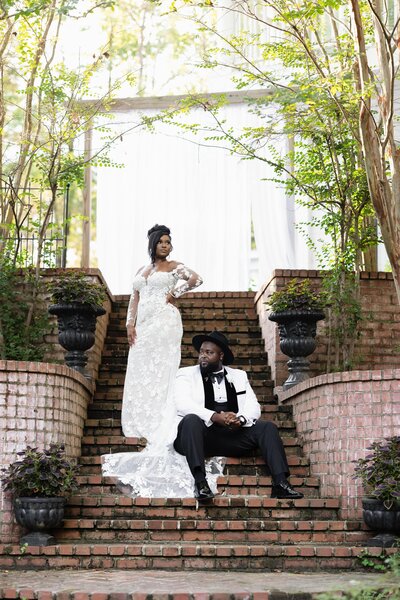 Bride in a white wedding dress with a veil, holding a colorful bouquet on a staircase at The Cadre in Memphis.