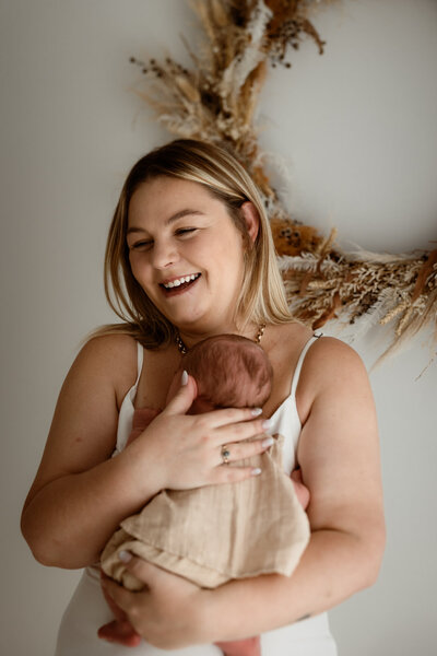 mother hodling onto her newborn baby in brisbane photography studio in brookwater