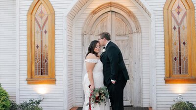 Groom kisses bride on the forehead outside of a church