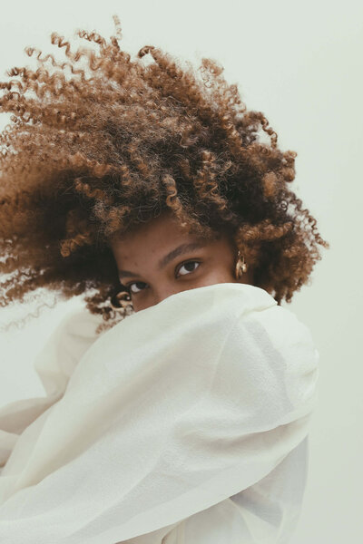 a black women with curly brown hair models a white shirt