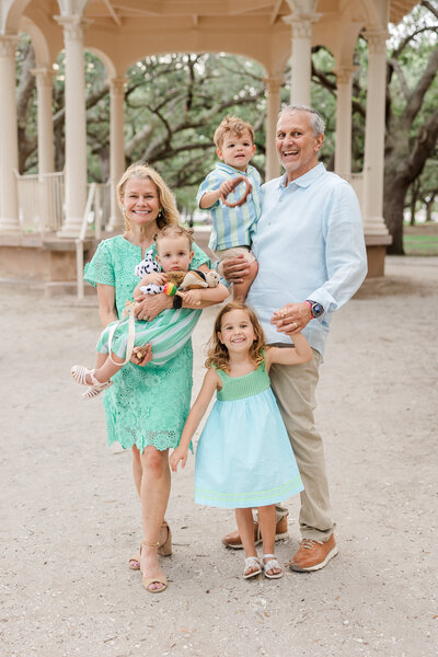 five members of a family with their white dog photographed wearing light blue and white at Hampton Park Charleston SC