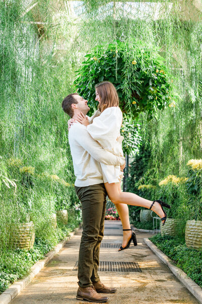 Man picking up woman while standing on pathway in garden