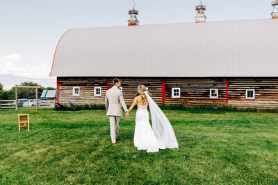 Bride and groom walking near red barn at Staubach Creek Ranch in Winston, MT