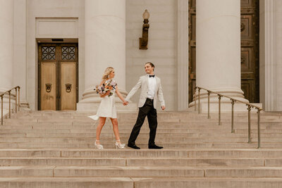 couple walking on courthouse steps after city elopement