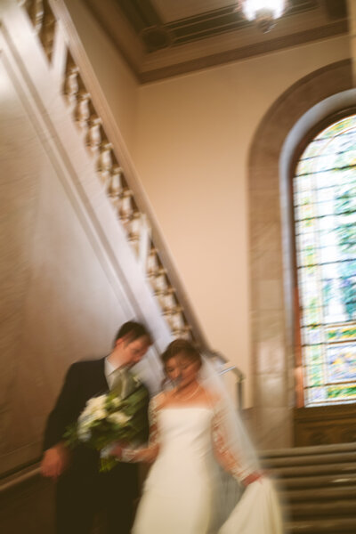 Blurry, romantic moment of bride and groom descending grand staircase