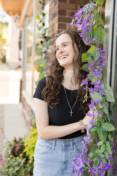Senior girl standing amongst flowers smiling at the camera