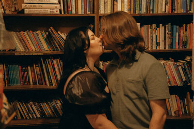 Two people kissing in a bookstore.