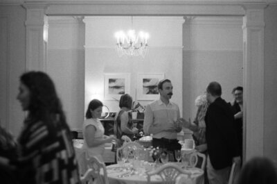 candid film photo of wedding guests mingling in victorian dining room