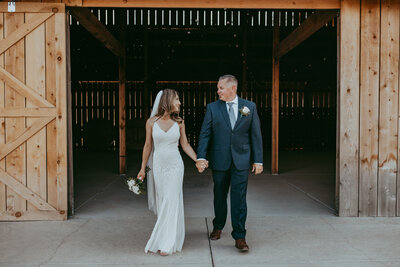 A bride and groom holding hands and walking together at [venue name].