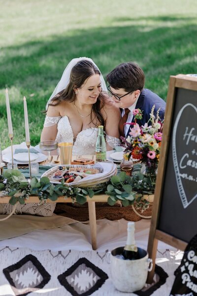 LGBTQ brides enjoy picnic together during backyard wedding in Colorado.