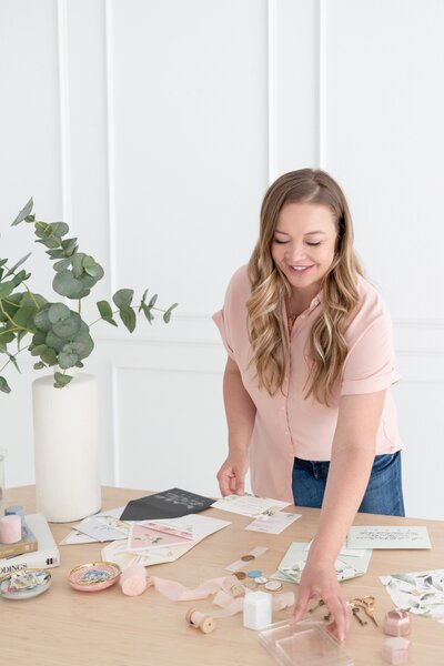 Smiling woman arranging paper goods and calligraphy supplies on a desk