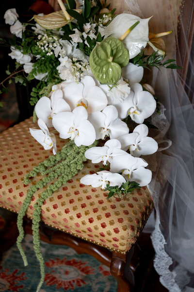 photo of bridal bouquet of orchids laying in dining room chair taken by Sea Island Wedding Photographer, Rhonda Rowell