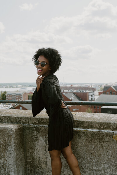 Jessica in a nuuly black dress at the top of a parking garage.
