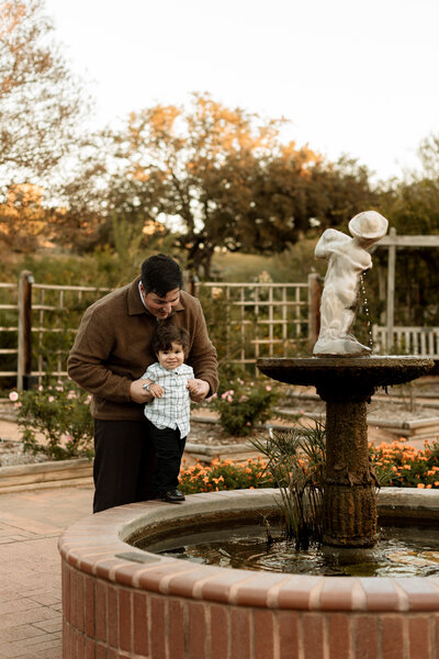 dad holding toddler boy on fountain