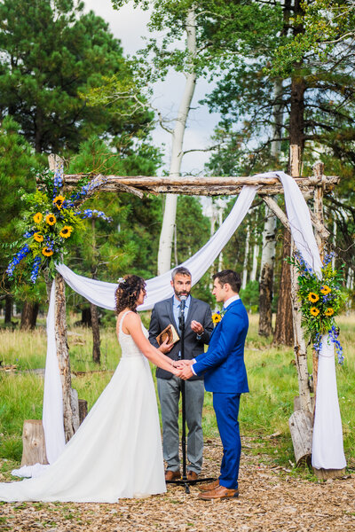 Flagstaff Nordic Village wedding photography sunflower arch ceremony bride and groom holding hands aspens