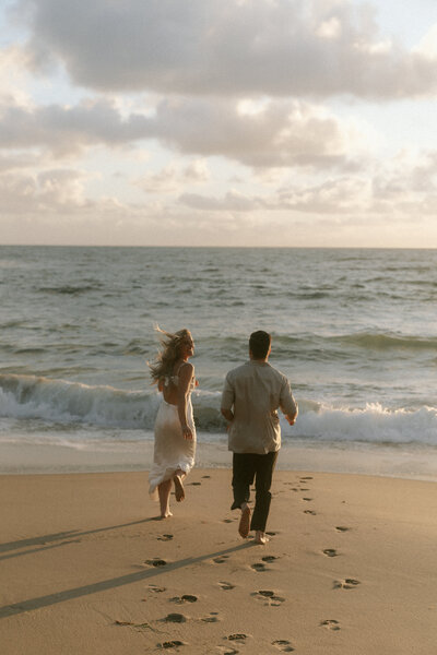 Husband and wife running into the pacific ocean