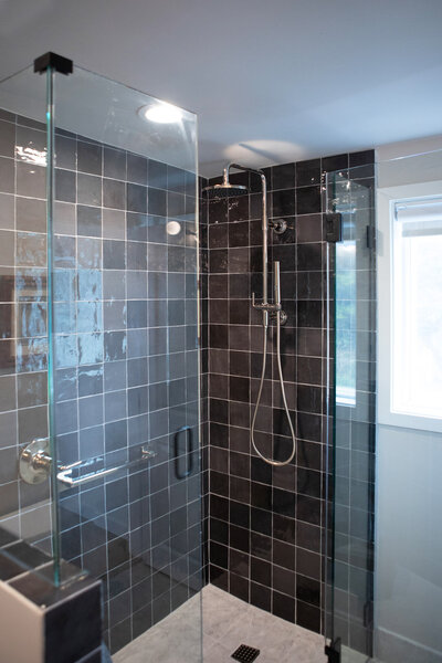 Beach house renovation shower details featuring a black and gray tiled backsplash.
