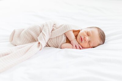 newborn baby boy laying on bed swaddled