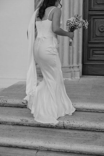 Bride walking up stairs, in black and white.