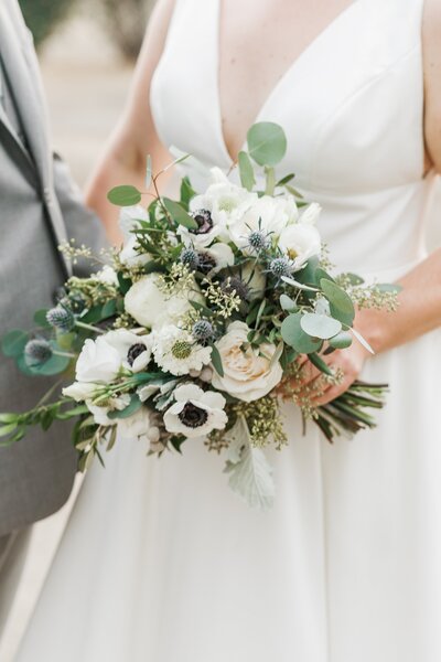 Bridal bouquet with white poppy anemones, thistle, and champagne roses