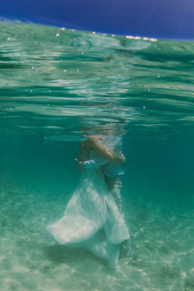 bride and groom hugging underwater