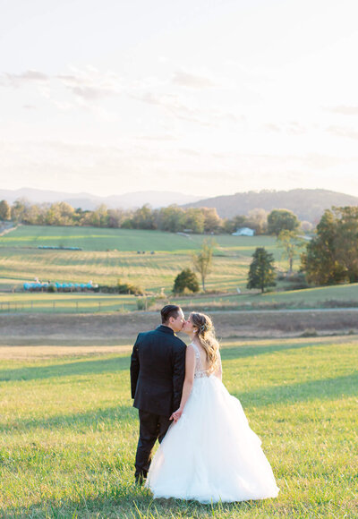 Bride and Groom kissing near the mountains at sunset. Captured by Charlottesville Wedding Photographer Bethany Aubre Photography.